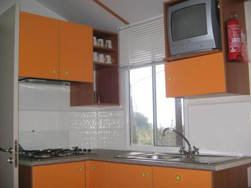Una cocina con gabinetes naranjas y un fregadero y una ventana. en Camping Helios Triscina, en Triscina
