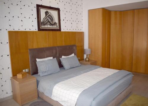 Un dormitorio con una cama grande con cabecero de madera. en Villa Lalla Laroussa, en Kenitra