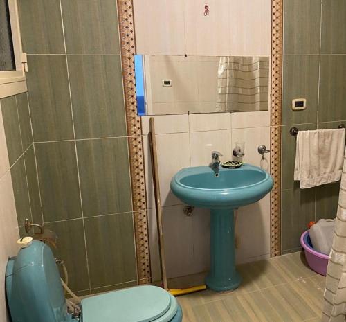 Un baño con un lavabo azul y un inodoro. en Fully furnished family apartment, en Banī Ghālib