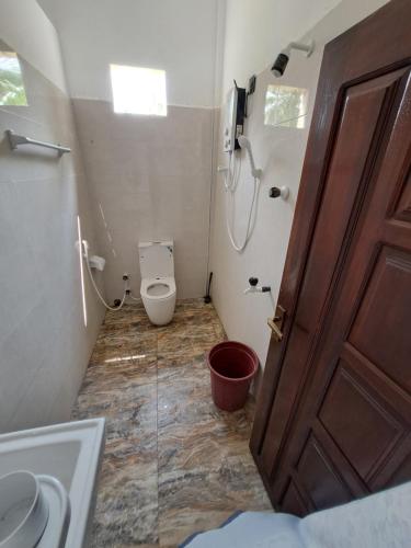 a bathroom with a toilet and a shower and a door at Palm Breeze Kokuvil in Jaffna