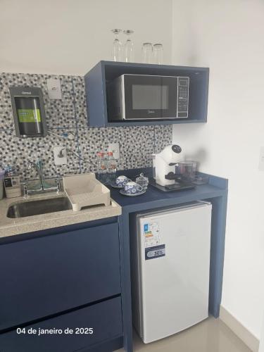 a kitchen with a sink and a microwave above a refrigerator at Studio | Expo Stay Tucuruvi Metro |Swimming pool in São Paulo
