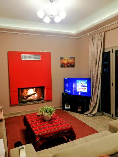 uma sala de estar com uma lareira vermelha e uma TV em Fella Chalkida em Chalkida