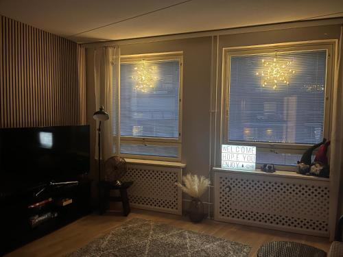 ein Wohnzimmer mit 2 Fenstern und einem TV in der Unterkunft Great two bedrooms apartment with a sea view from the balcony close Helsinki center in Helsinki