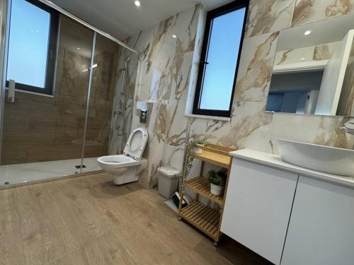 a bathroom with a toilet and a sink and a shower at Bright & cozy apartment in Livadia in Livadhia