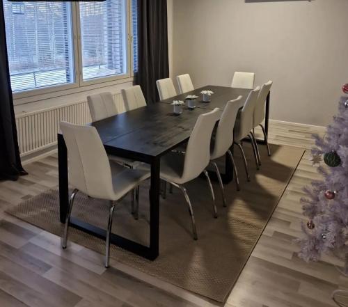 a dining room table with white chairs and a christmas tree at Santa's choice for Aurora hunters , Sauna and jacuzzi in Rovaniemi