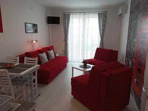 a living room with red couches and a table at Studio La Casa in Soko Banja