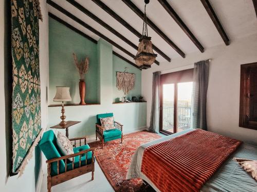 a bedroom with a bed and two chairs and a window at Finca Flamenco Holiday Suites Adults Only in Pizarra
