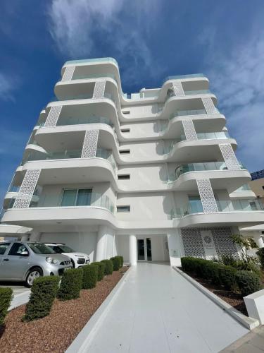 Un edificio blanco con un coche aparcado delante. en Elite 1BD Flat with Pool in Harbor area, en Lárnaca