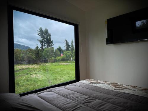 a bedroom with a large window looking out at a field at Refugio Nauru in Puerto Dunn