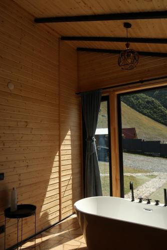 a bath tub in a room with a window at Kazbegi Inn Cottages in Kazbegi
