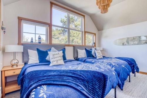 two beds in a room with two windows at Sunshine and Sweaters in Pacific City