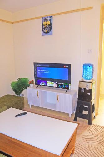 ein Wohnzimmer mit einem Flachbildfernseher auf einem Fernsehtisch in der Unterkunft Anifar cozy home in Kahawa