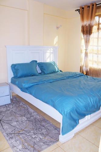 ein Schlafzimmer mit einem Bett mit blauen Laken und einem Fenster in der Unterkunft Anifar cozy home in Kahawa
