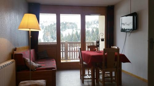 een eetkamer met een rode tafel en stoelen en een televisie bij Appartement Super-Dévoluy in Le Dévoluy