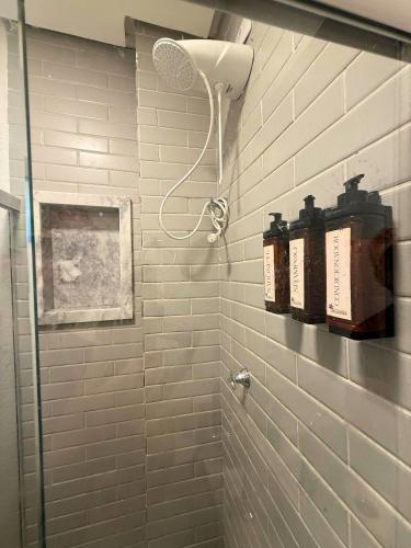 a white tiled shower with a shower head in a bathroom at MHV Milagres - Studio Guadalupe 05, quarto e sala privativo a poucos metros da Praia do Marceneiro in Passo de Camarajibe