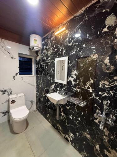 uma casa de banho em mármore preto com um WC e um lavatório em le hut residency em Pondicherry