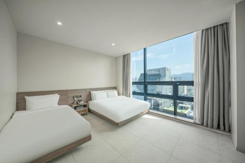 a hotel room with two beds and a large window at Daegu Dongseongro Giant Hotel in Daegu