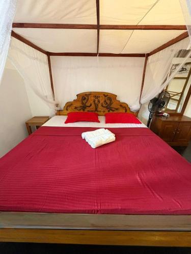 迪克韦勒Baron Nilwella的帐篷里的一张床，铺着红色的床单和红色的枕头