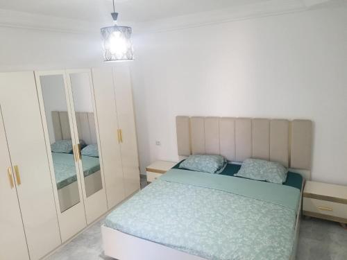 a small bedroom with a bed and a mirror at Appartement Oasis Chenini Gabes in Shanīnī
