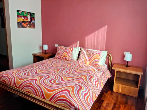 a bed with a colorful comforter and two side tables at Casa Mike - Trilocale con garage in San Giuliano Milanese