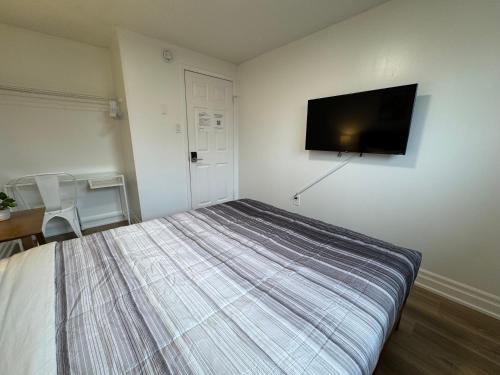 a bedroom with a bed and a flat screen tv at North Barrie !E Stylish and Cozy Private Bedroom with Shared Bathroom in Barrie