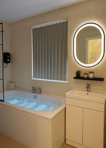 a bathroom with a tub and a sink at Lux 4 Bedroom House - Jacuzzi Bath Sleeps 9 Free Parking Near Leeds Centre in Leeds