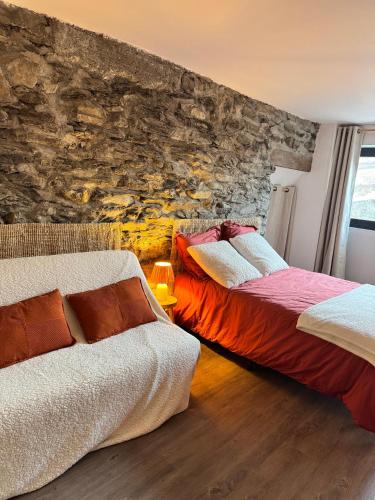 two beds in a room with a stone wall at Les Écrins d'or - Maison Les Deux Alpes in Les Deux Alpes