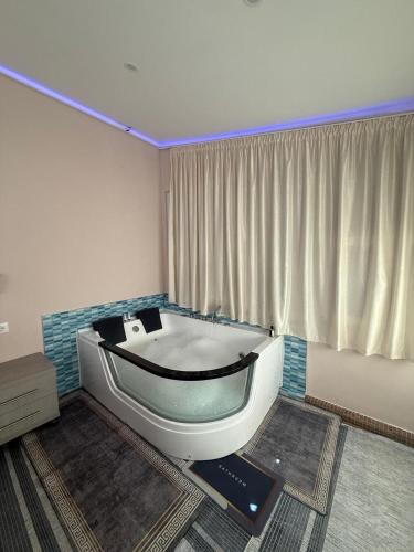 a bath tub sitting in a room with a window at Hotel Bardhi in Kuçovë