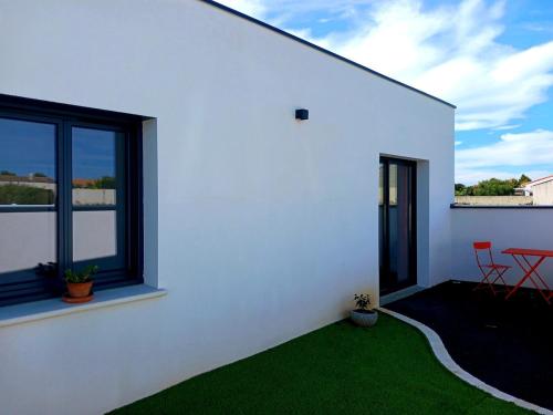 ein weißes Haus mit einem Garten mit grünem Gras in der Unterkunft appartement individuel T2 in Soubise