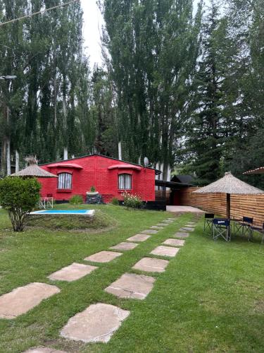 a red house with a table and a bench and a yard at Complejo el trébol in Potrerillos