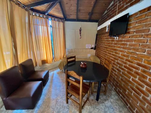 Habitación con mesa, sillas y pared de ladrillo. en Complejo el trébol, en Potrerillos