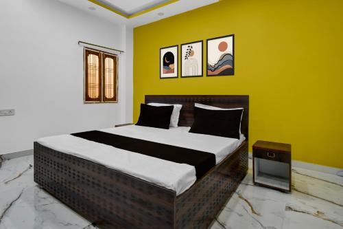ein Schlafzimmer mit einem großen Bett an einer gelben Wand in der Unterkunft Hotel O DP Palace in Banthra Sikandarpur