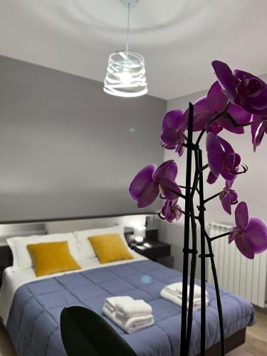 a vase with purple flowers in front of a bed at ILBE bed & breakfast in Campobasso