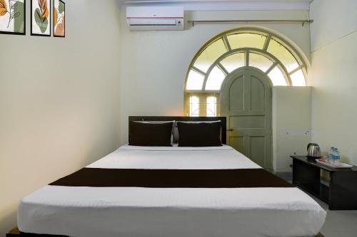 a bedroom with a large white bed with a window at POP 84116K Hotel O Maa Tara Guest House in Dum-Dum Junction