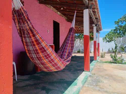 une maison rouge et rose avec un hamac suspendu dans l'établissement Hostel Mamitchesca - Redes e Barracas, à Aracati