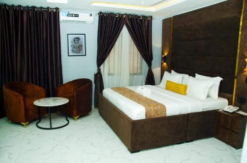 a hotel room with a bed and a chair at El-Nido Hotel by Kdove in Omole