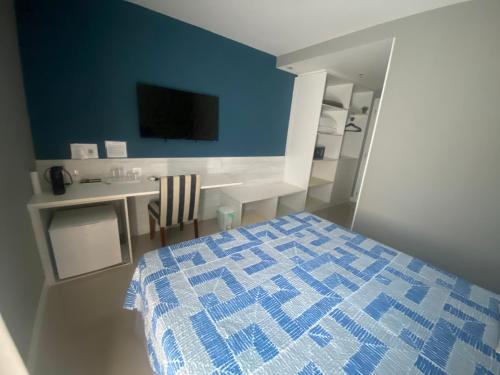 Schlafzimmer mit einem blauen und weißen Bett und einem Schreibtisch in der Unterkunft Hotel em CABO FRIO Cond Royale - Av Assunção 239 Bairro Passagem ap 305 in Cabo Frio