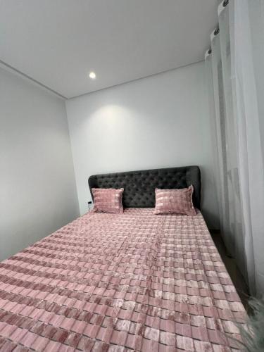 1 dormitorio con 1 cama con almohadas rosas en Appartement à louer, en Sousse