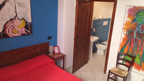 a bedroom with a red bed and a bathroom at Bed & Breakfast Maredomus in Milazzo