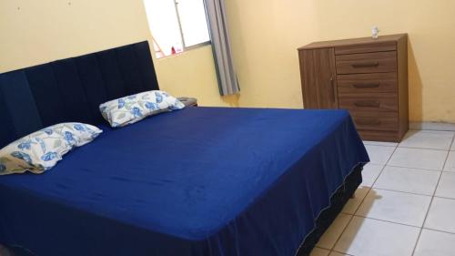 un letto blu con cuscini e un comò in una camera da letto di Casa da Ana ad Ananindeua