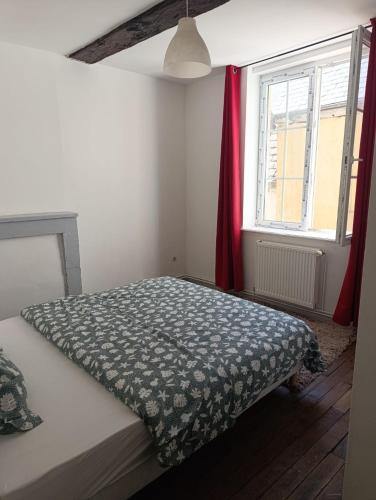 a bedroom with a bed and a window with red curtains at Appartement Cosy du château in Sedan