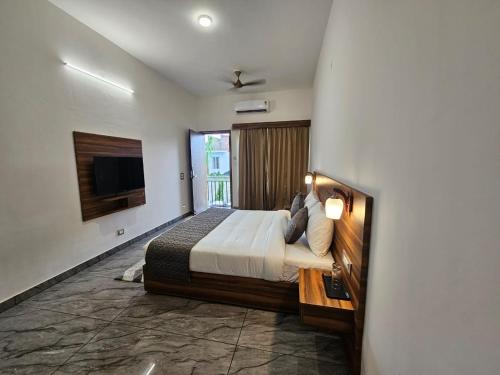 una camera da letto con un letto grande e una televisione di Corbett Crown Resort a Ramnagar