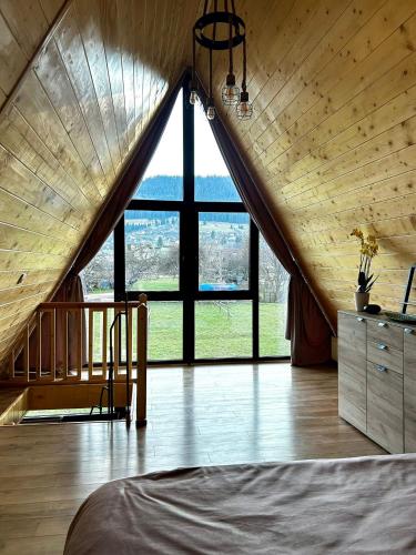 ein Schlafzimmer mit einem großen Dachboden und einem großen Fenster in der Unterkunft BucovinaAframe in Câmpulung Moldovenesc