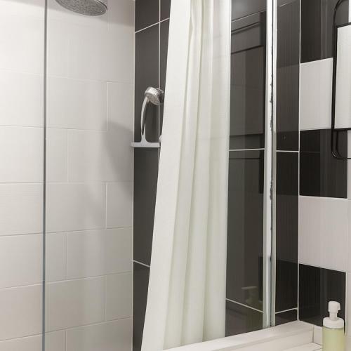 a shower with a white shower curtain in a bathroom at Studio moderne, cosy & lumineux Chez Suzanne in Angers
