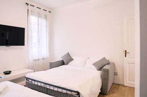 a white bedroom with a bed and a tv at Dimora Castelli Free Parking in Marghera