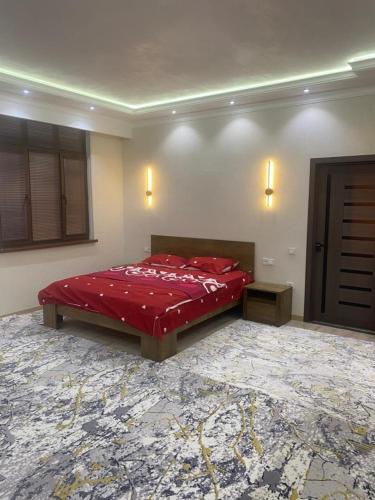 a bedroom with a bed with a red comforter at Best Apartments in Khujand