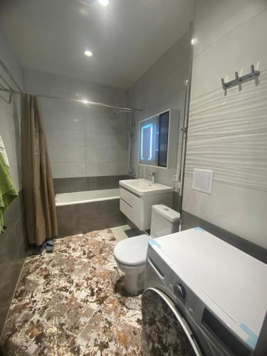 a bathroom with a toilet and a sink and a tub at Best Apartments in Khujand