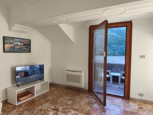 een woonkamer met een televisie en een glazen schuifdeur bij Casa Vacanze Terramare in Bogliasco