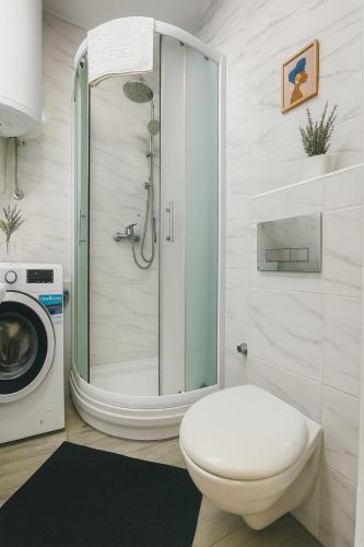 a bathroom with a shower and a toilet and a washing machine at Studio IKA Belgrade Airport Free Parking possible Self Check-In Terrace in Ledine