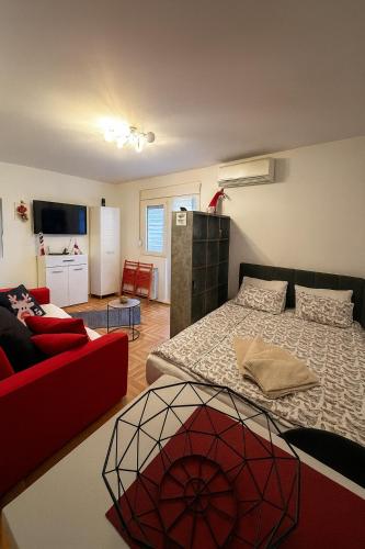 ein Schlafzimmer mit einem Bett und einer roten Couch in der Unterkunft Studio IKA Belgrade Airport Free Parking possible Self Check-In Terrace in Ledine